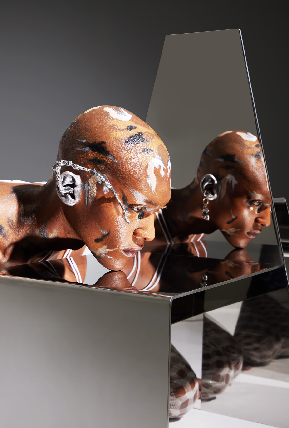 Copper body paint reflected in mirrored sculpture